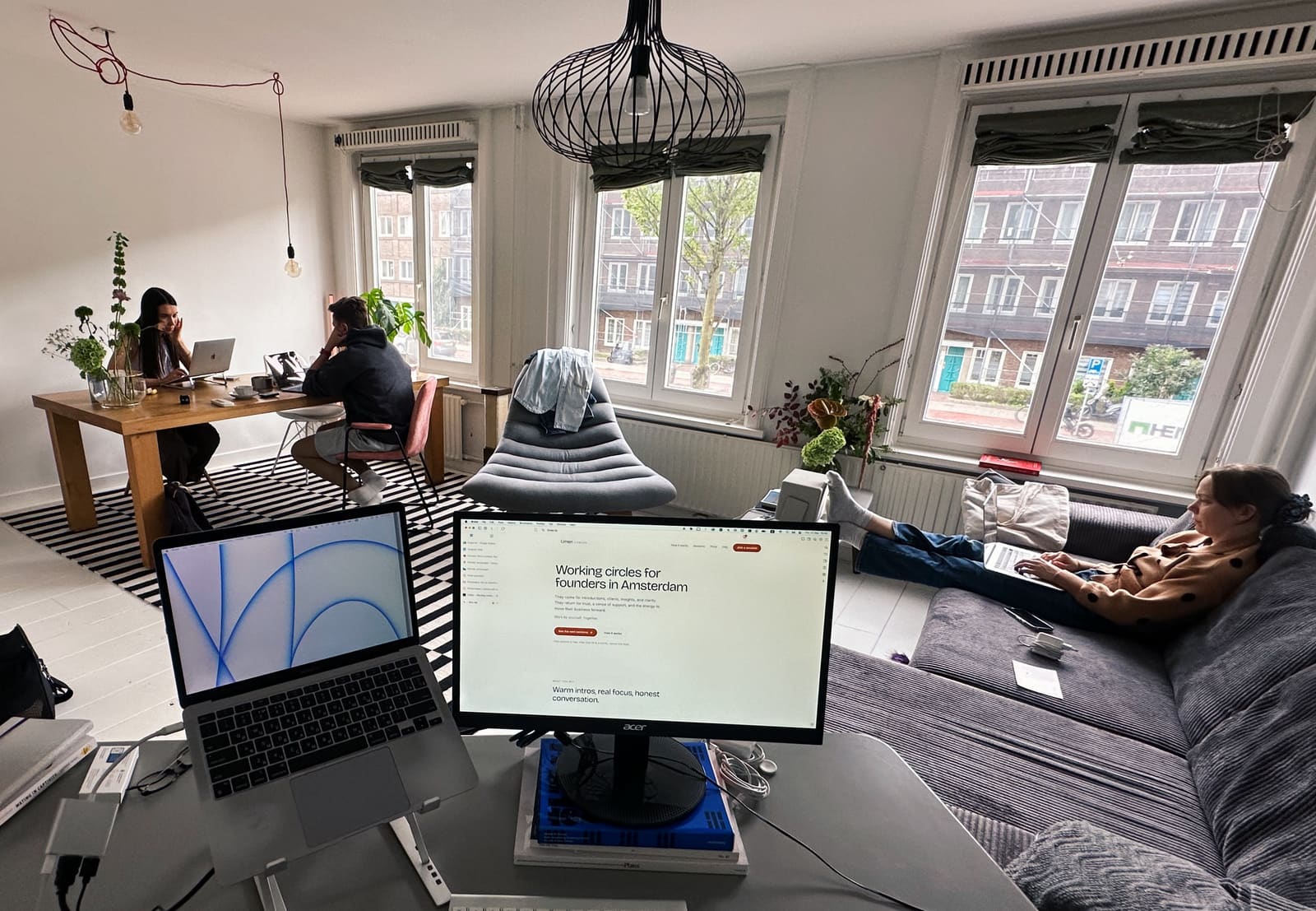 A small group working together in an apartment, with the Limen Cowork site open on a monitor.