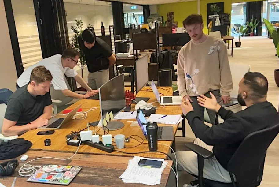 Five people talking and working around one long table during a Limen session