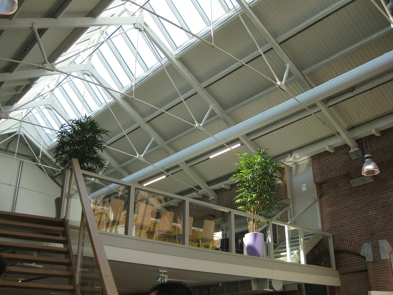 The library under the glass roof of De Hallen, with tables on the mezzanine